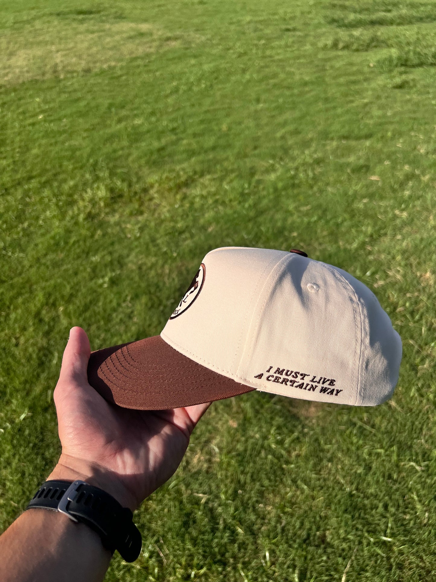 Hand holding a cap with text on a grassy background